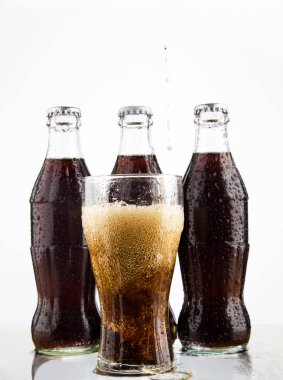 Moskova, Rusya - 22 Haziran 2013: Üç klasik kola şişeleri ve Coca-Cola, şeffaf cam gri arka plan üzerinde.