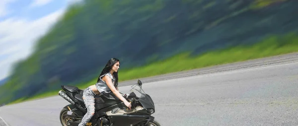 黒のスポーツ バイクに座って美しいブルネットの女性の肖像画 デニムのベストを身に着けている非常に熱いセクシーな若い女の子 — ストック写真
