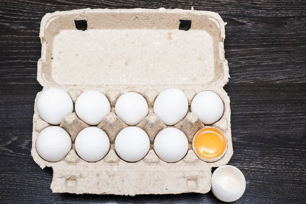 eggs in egg tray, one egg  cracked. Group of white fresh eggs