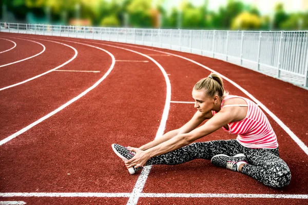 Runner kadın egzersiz önce - açık atış germe. Stadyum egzersiz yaparak spor kız.