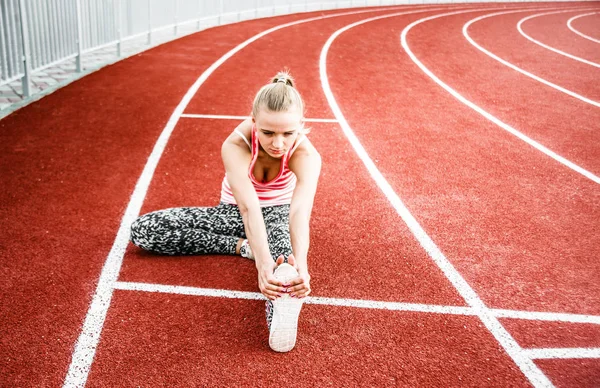 Runner kadın egzersiz önce - açık atış germe. Stadyum egzersiz yaparak spor kız.