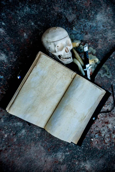 human skull with open magic empty book, candles and black knife lie