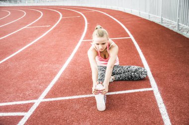 Runner kadın egzersiz önce - açık atış germe. Stadyum egzersiz yaparak spor kız.