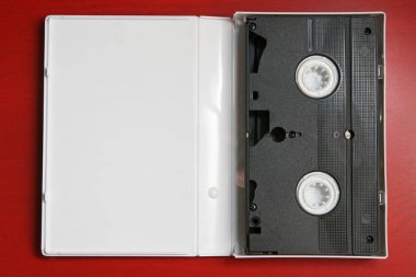 Raster video kaset izole kırmızı zemin üzerine şeffaf plastik ambalaj kutusu içinde.