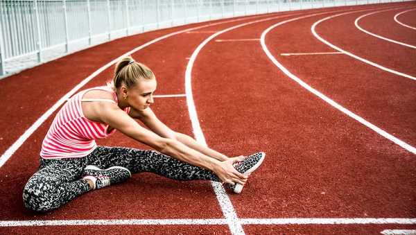 Runner kadın egzersiz önce - açık atış germe. Stadyum egzersiz yaparak spor kız.