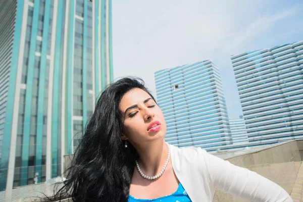 Portrait of serious young woman with  eyes closed .Portrait of a young asian businesswoman posing near modern office buildings