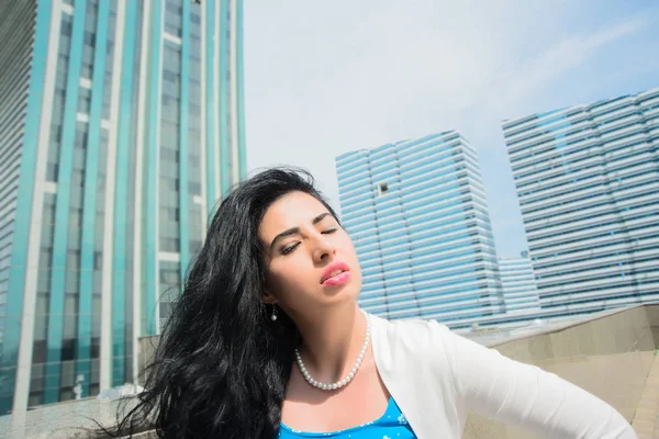 Portrait of serious young woman with  eyes closed .Portrait of a young asian businesswoman posing near modern office buildings