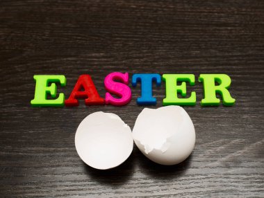 siyah arka plan ve kelime üzerinde kırık boş beyaz yumurta Paskalya renkli harfler yaptı.