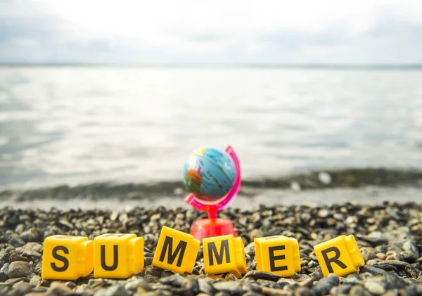 globe and summer  word made of cubes with letters. beach, coast background.