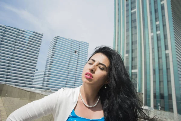 Portrait of serious young woman with  eyes closed .Portrait of a young asian businesswoman posing near modern office buildings