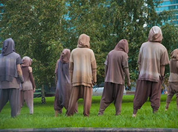 back rear view of fashionable men and women wearing  brown costumes with hoods