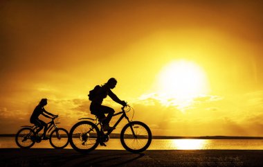 Boş alanı. Günbatımı Bisiklet sportif arkadaşlar. Sahil boyunca binmek bisikletçiler. Spor doğa arka planda.