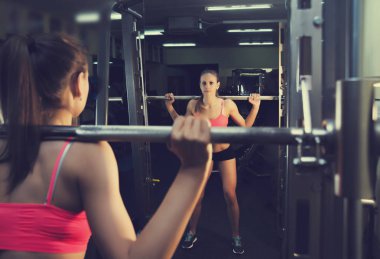 metal barbell ile çalışma ciddi atlet kız portresi. spor giyim güzel kadın spor salonu içinde eğitiyor. 