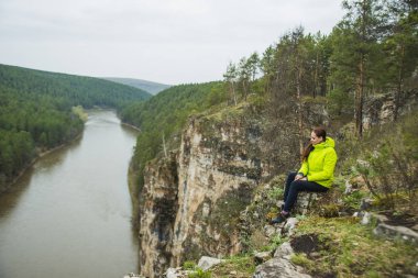 Dağ taş hızlı Nehri yakınında kenarında oturan yalnız kız. kadın dinlenmek ve rahatlamak soğuk taşa. Fikir kavramı hızlı zaman symbol.spring su. Kar yalan arazi. siyah deri ayakkabı