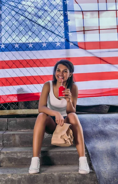 Стильная молодая афро-американка пьет красную колу из металлической банки. — стоковое фото