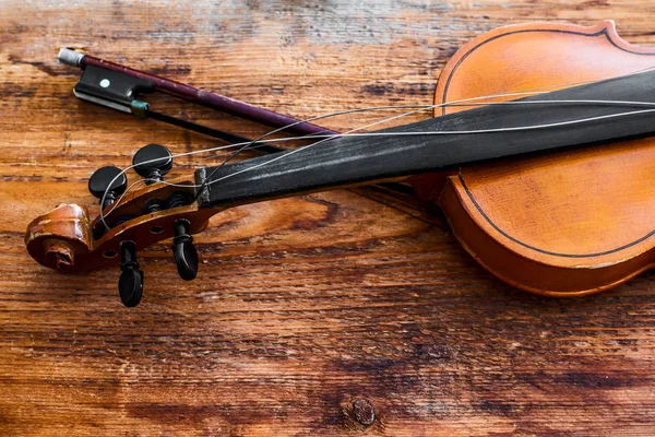 Violin and bow on a brown wooden table background.