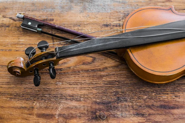 Violin and bow on a brown wooden table background.