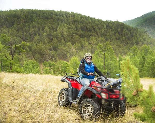 Motorsport With the ATV. Excited young man on quad bike. Happy young man driving all terrain vehicle in nature.