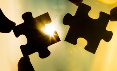 Gökyüzü arka planında yapboz parçaları olan eller. 