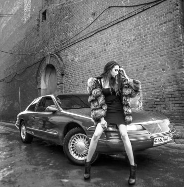 Omsk, Rusya Federasyonu - 14 Şubat 2017: kısa siyah elbise ayakta yakınındaki retro araba Lincoln Mark 8, sıcak sıcak giysiler - kadında genç kadın kürk ceket, siyah bot.