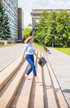 Genç ve güzel bir iş kadını evrak çantasıyla merdivenlerden iniyor. 