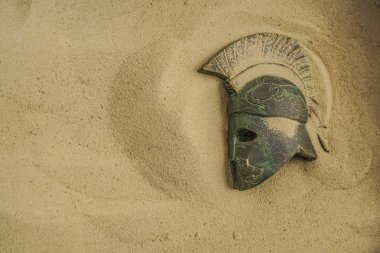 helmet of ancient warrior in sand. Roman  helmet with the Iroquois. Archaeology and paleontology concept clipart
