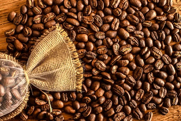 荒い生地の多くのコーヒー豆 木製の背景に黄麻から作られたバッグでのコーヒー豆 — ストック写真