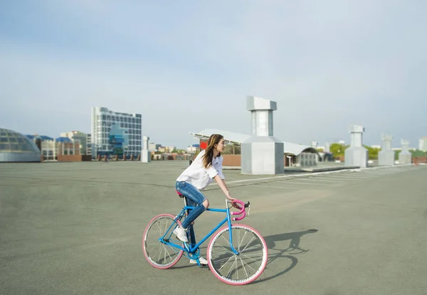 hipster girl  is riding bike on a city street  background. Empty space for design.