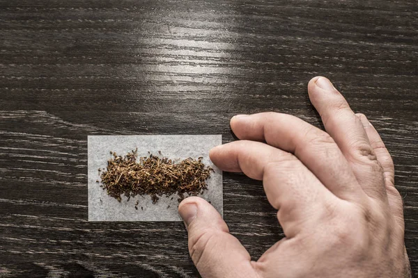 Hand Dreht Ein Zigarettenpapier Mit Tabak Schwarzen Holztischhintergrund — Stockfoto