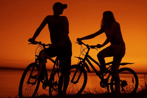 Αθλητικοί Φίλοι Ποδήλατα Ηλιοβασίλεμα Σιλουέτα Ζευγαριού Κατά Μήκος Της Ακτής — Φωτογραφία Αρχείου