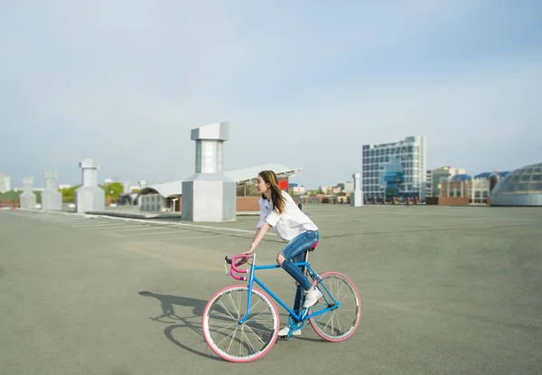hipster girl  is riding bike on a city street  background. Empty space for design.
