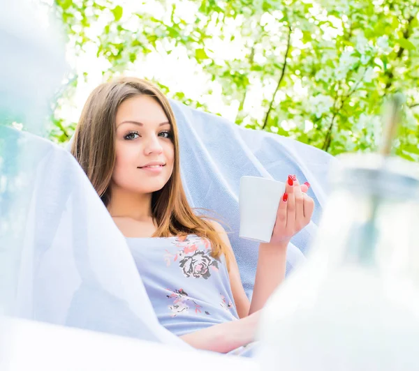 在夏日公园喝咖啡的白色扶手椅上 长着棕色长发的快乐女孩的肖像 — 图库照片