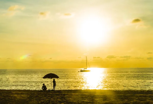 日落时分在海滩上享受度假的人们的剪影 — 图库照片
