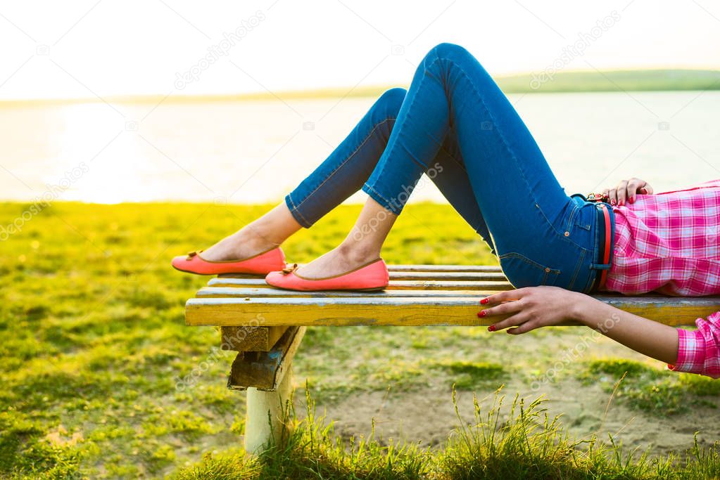 no face. unrecognizable person. Attractive female legs on the bench at the beach.