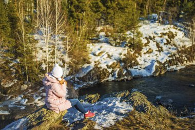 Dağ taş hızlı Nehri yakınında kenarında oturan kız.