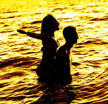Gün batımında suda duran iki genç yetişkin aşıklar 