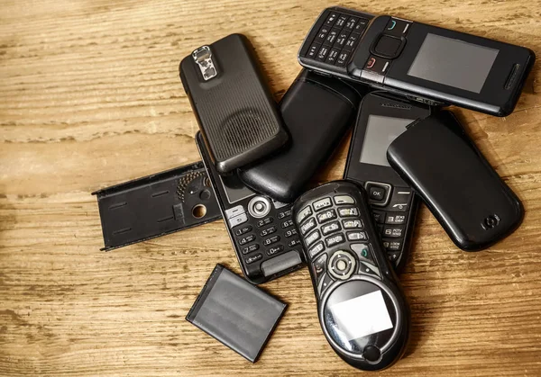 used, old mobile cell phones with batteries   on wooden table background.