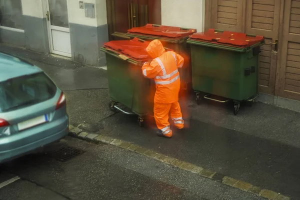 Мужчина Носит Оранжевую Форму Ходит Мусорным Баком Улице Дождливый День — стоковое фото
