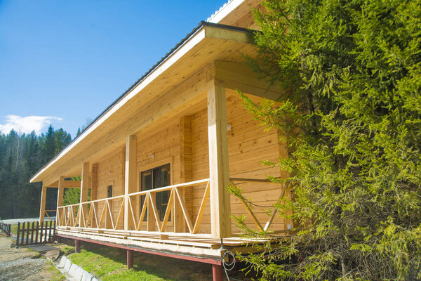 wooden log house facade against cloudy sky background. Facade of a beautiful house with green garden, summer day