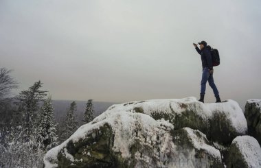 Sırtında sırt çantasıyla ve kalın giysileriyle kışın uzak diyarlarına bakan bir adam..