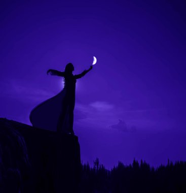 Dağın tepesinde duran siluet kadın. Dişi, elinde büyüyen ayı orman ağaçlarının üzerinde tutuyor. arka plan ve ay ışığı. 