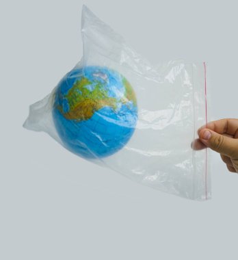 Beyaz arka planda Dünya küresi ile plastik poşet tutan bir adam var..