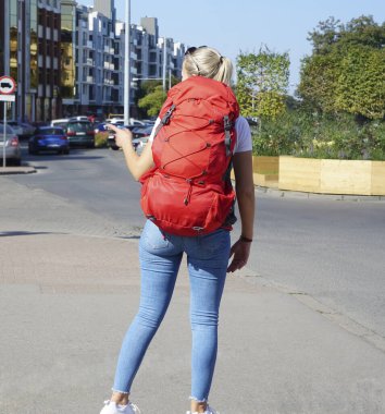 Arka manzaralı gezgin kız. Kültür Şehri Yayaları 'nda kırmızı kadın sırt çantası ve turizm kıyafeti yakın.
