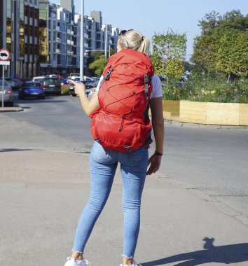Arka manzaralı gezgin kız. Kültür Şehri Yayaları 'nda kırmızı kadın sırt çantası ve turizm kıyafeti yakın.