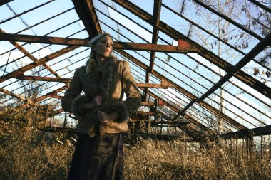 Sarışın, orta yaşlı bir kadın terk edilmiş bir serada, kurumuş çalılar ve kuru uzun otlar içinde.. 