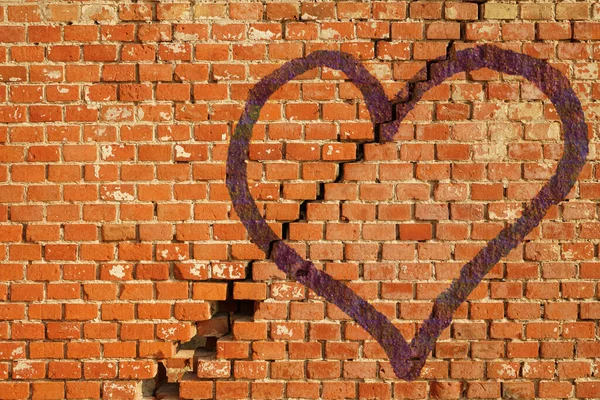 blue broken heart on red brick wall with big crack in the middle. Concept of broken love.