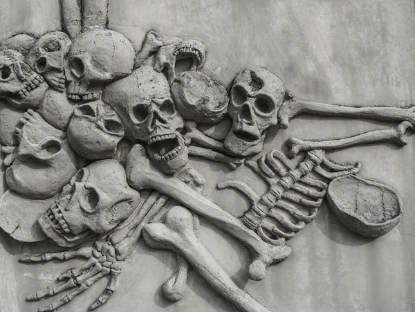 Pile of human skulls on stone surface. Wall of Skulls. A stone wall with skull carvings.