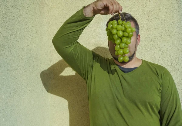 髭の男は緑のブドウの束を保持 — ストック写真