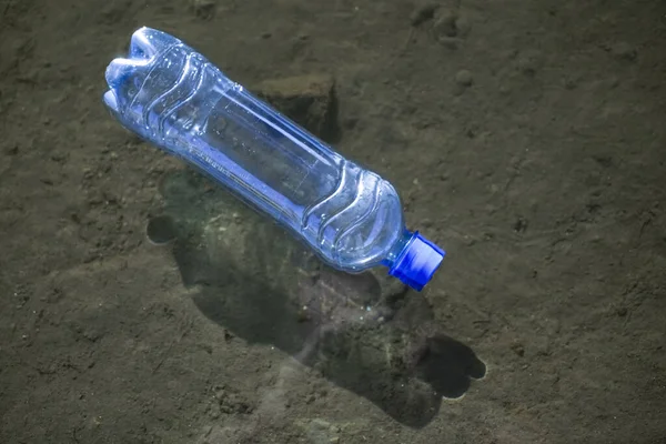 plastic waste at the ocean, a plastic bottle floating in  sea at the water surface, environmental problem with plastics pollution, copy space for text. sun light and shadow.