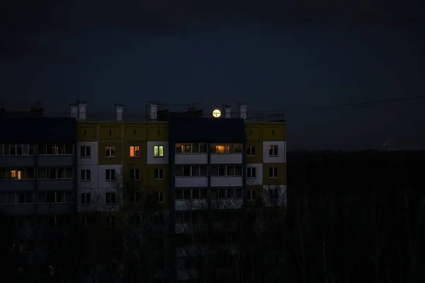 full moon  in the dark sky over the roofs of the night city